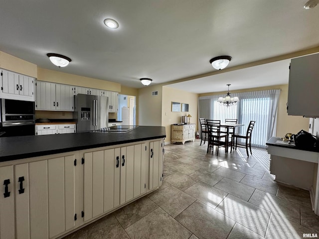 kitchen featuring black appliances, a chandelier, hanging light fixtures, and white cabinets