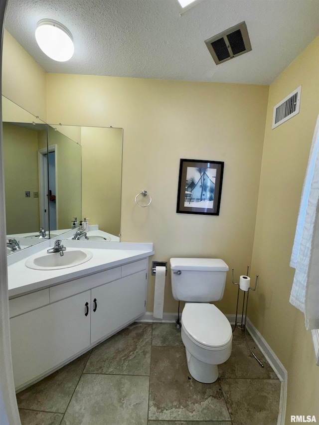 bathroom with toilet, vanity, and a textured ceiling