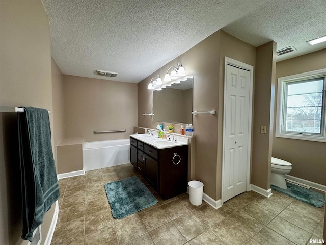 bathroom featuring toilet, vanity, a textured ceiling, and tile patterned flooring