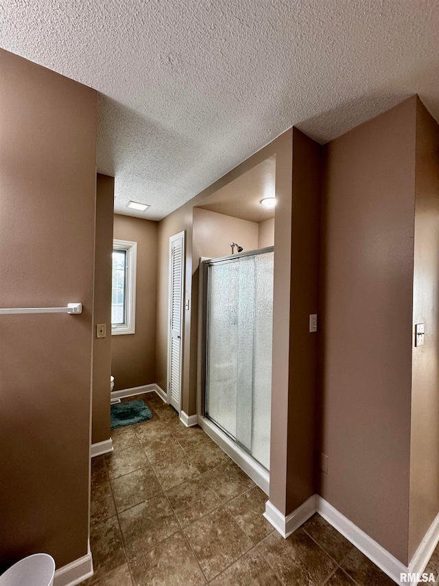 bathroom with walk in shower, tile patterned flooring, and a textured ceiling