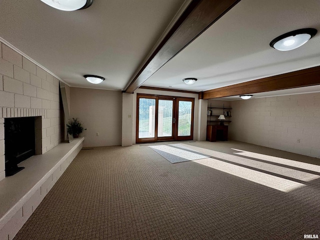 unfurnished living room featuring carpet, a large fireplace, brick wall, and beamed ceiling