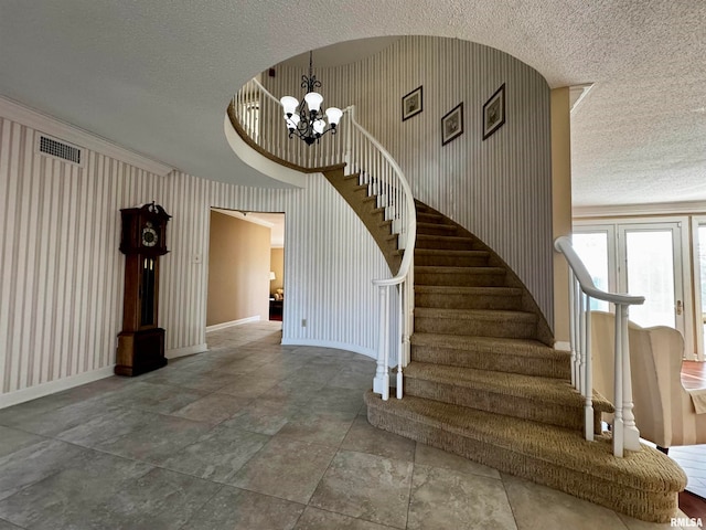 stairway featuring a textured ceiling and a chandelier