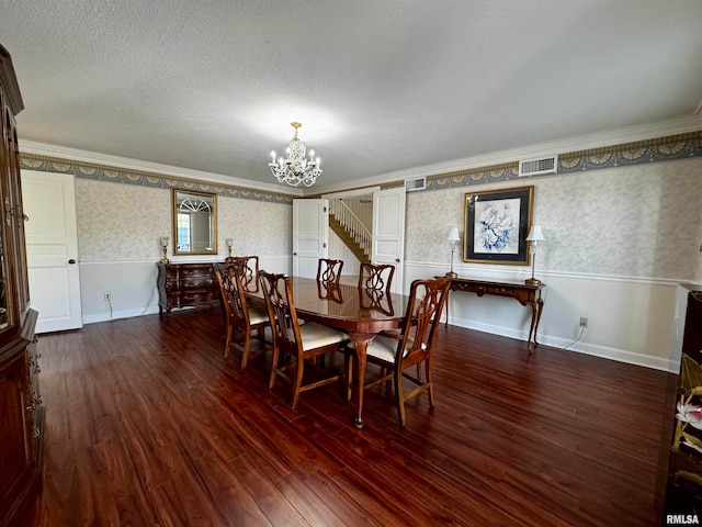 dining area featuring dark wood-type flooring, a textured ceiling, crown molding, and a notable chandelier