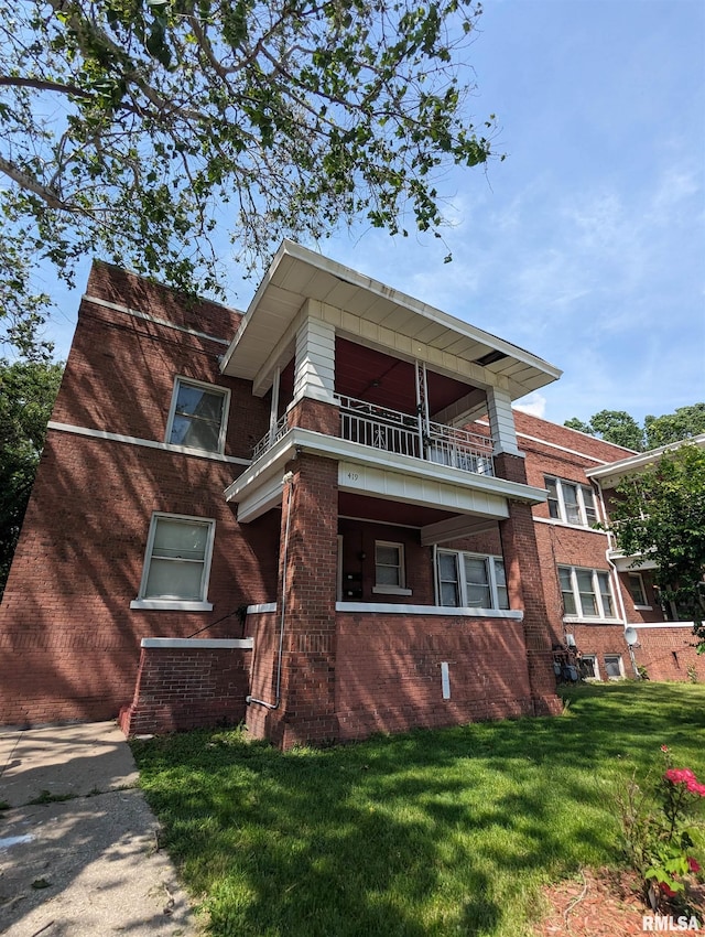 view of front of property featuring a front yard and a balcony