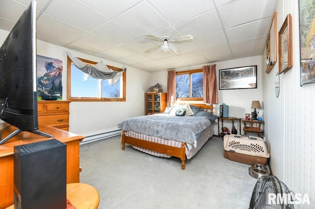 bedroom with a paneled ceiling, ceiling fan, and a baseboard heating unit