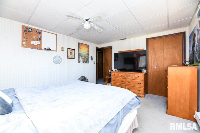 bedroom with light carpet, a paneled ceiling, and ceiling fan