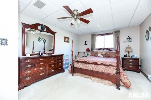 carpeted bedroom with ceiling fan and a drop ceiling