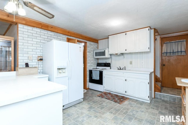 kitchen featuring white cabinetry, sink, ceiling fan, brick wall, and white appliances