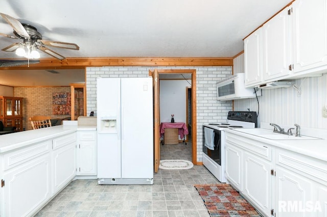 kitchen featuring ceiling fan, sink, brick wall, white appliances, and white cabinets