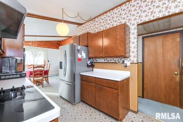 kitchen with pendant lighting, lofted ceiling, crown molding, stainless steel fridge, and range hood