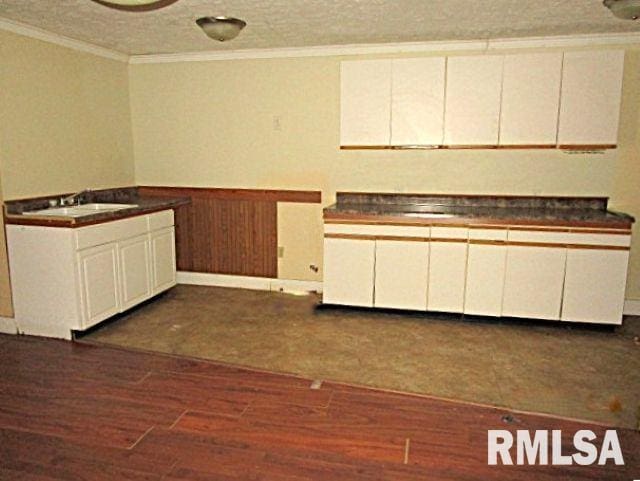 kitchen with a textured ceiling, sink, ornamental molding, dark hardwood / wood-style floors, and white cabinetry