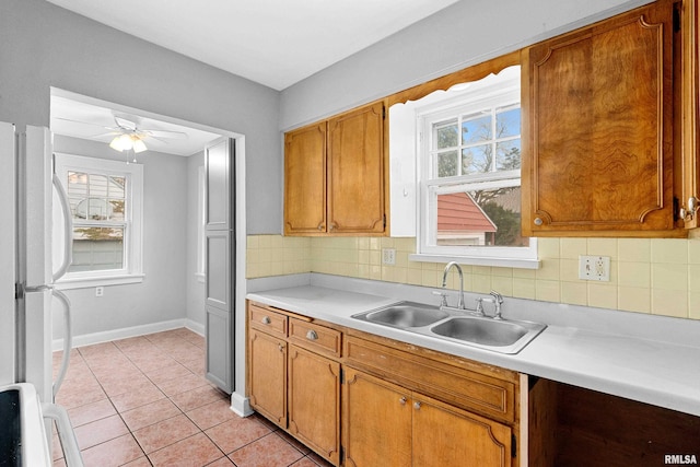 kitchen featuring tasteful backsplash, sink, white fridge, and light tile patterned floors