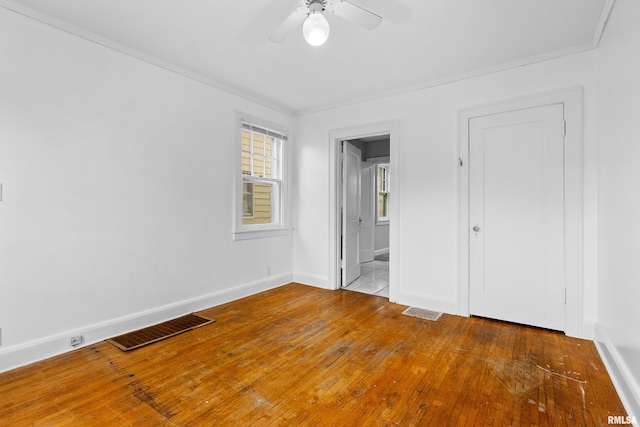 unfurnished bedroom with wood-type flooring, ensuite bath, ceiling fan, and crown molding