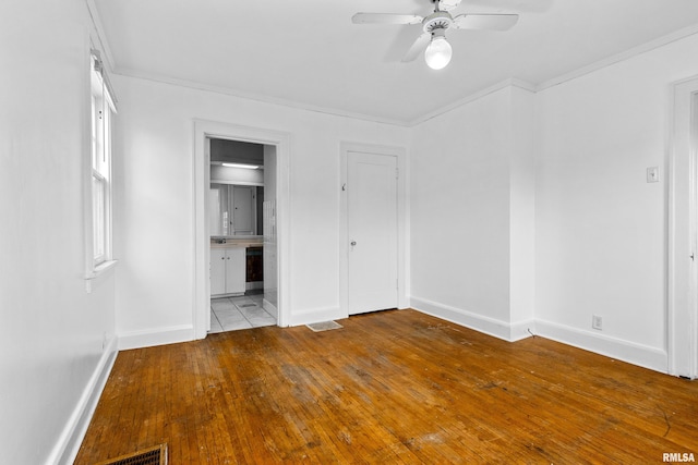 unfurnished bedroom featuring ornamental molding, connected bathroom, ceiling fan, and light wood-type flooring