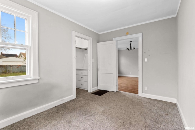 unfurnished bedroom featuring carpet flooring, a chandelier, and crown molding