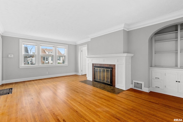 unfurnished living room with light wood-type flooring, a brick fireplace, and crown molding