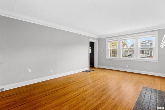 empty room with crown molding and light hardwood / wood-style floors