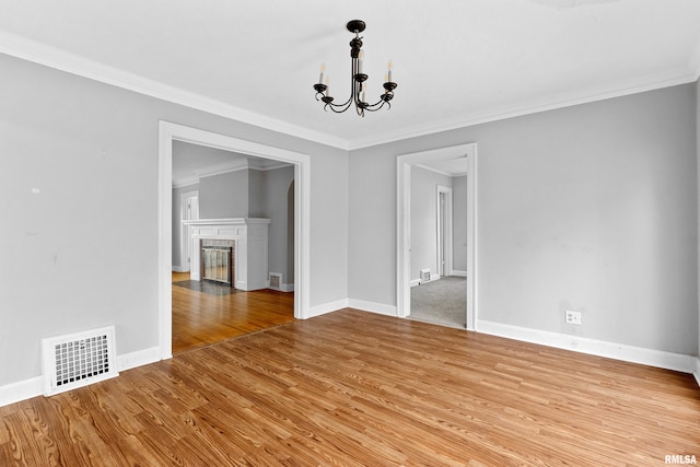 unfurnished dining area with ornamental molding, light wood-type flooring, and an inviting chandelier