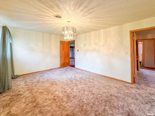 empty room featuring a textured ceiling, an inviting chandelier, and carpet