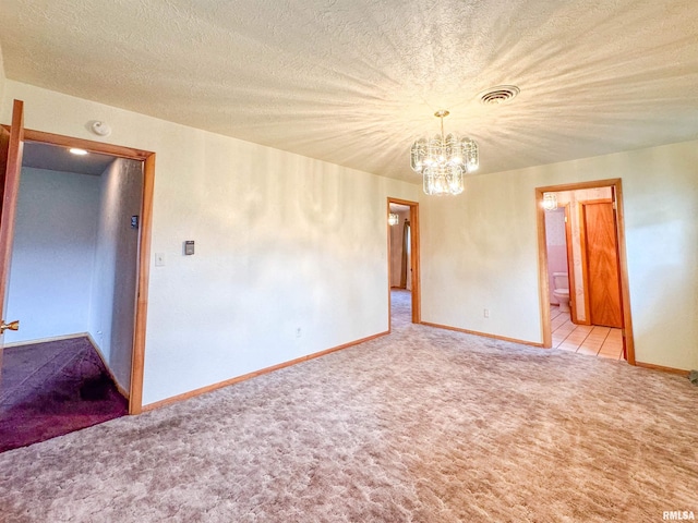 carpeted empty room with a textured ceiling and a notable chandelier