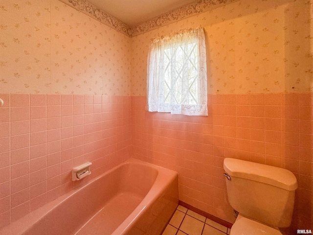 bathroom featuring tile walls, tile patterned floors, a bathing tub, and toilet