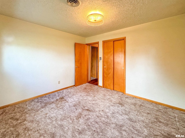 unfurnished bedroom with a textured ceiling, carpet flooring, and a closet