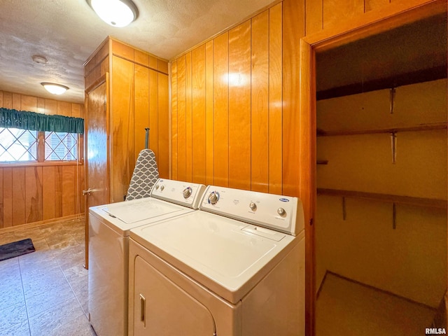 laundry room featuring washing machine and dryer, wooden walls, and a textured ceiling