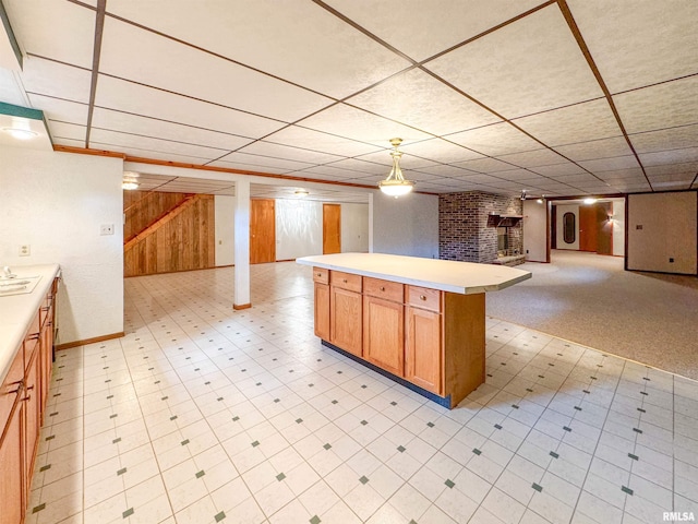 kitchen featuring a kitchen island, pendant lighting, wooden walls, and a paneled ceiling