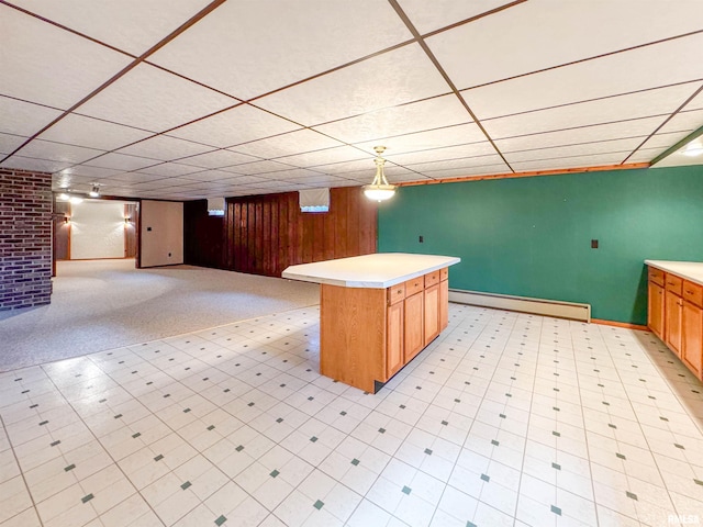 kitchen featuring a drop ceiling, a baseboard heating unit, decorative light fixtures, and a center island