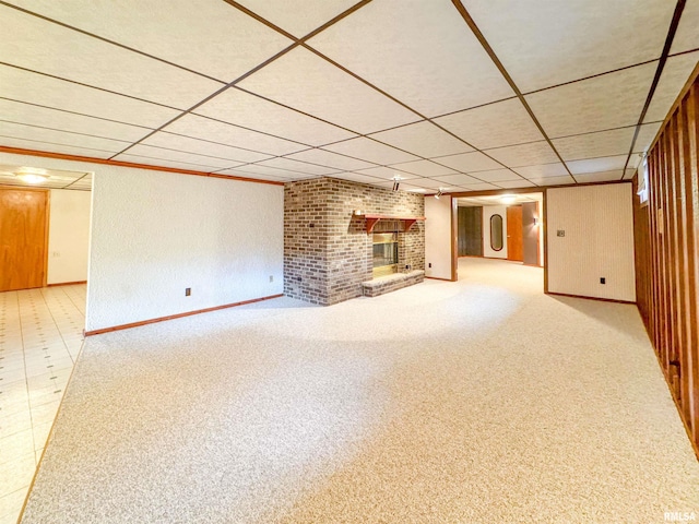 unfurnished living room featuring a paneled ceiling, light colored carpet, and a brick fireplace