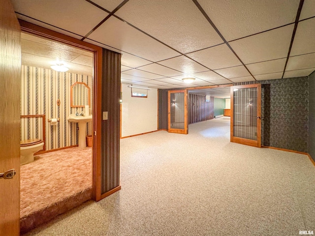 basement with a paneled ceiling and carpet flooring