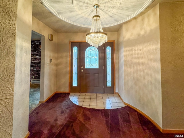 tiled foyer entrance featuring a textured ceiling, an inviting chandelier, and ornamental molding