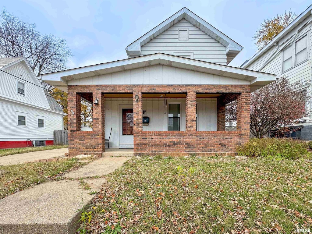 view of front of house featuring a porch, cooling unit, and brick siding