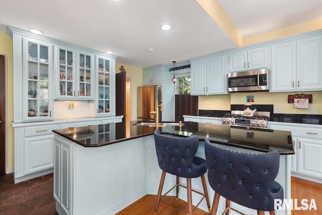 kitchen featuring white cabinets, appliances with stainless steel finishes, sink, and an island with sink