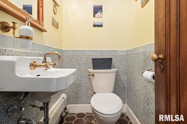 bathroom with toilet, tile walls, tile patterned flooring, and a baseboard heating unit