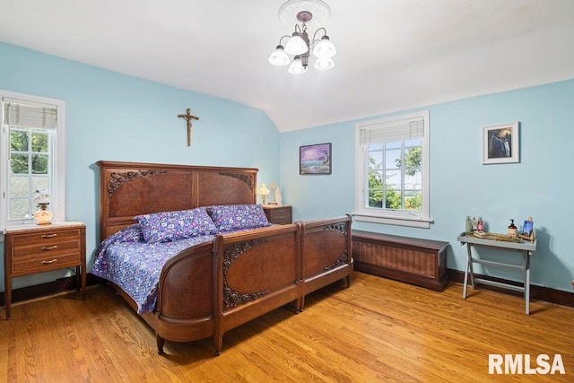 bedroom featuring vaulted ceiling, a notable chandelier, and light hardwood / wood-style flooring