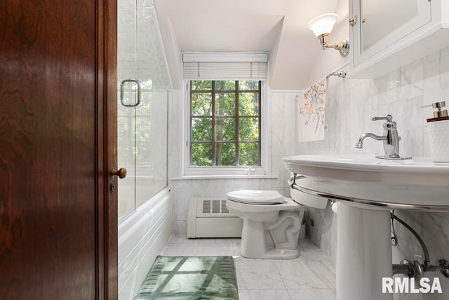 bathroom with tile walls, shower / bath combination with glass door, and toilet