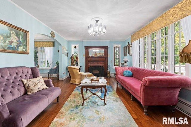 living room featuring a brick fireplace, dark hardwood / wood-style floors, an inviting chandelier, and baseboard heating