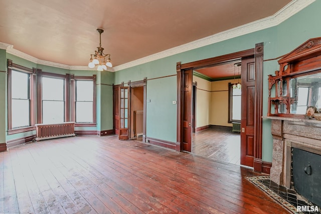 unfurnished living room with dark hardwood / wood-style flooring, a wealth of natural light, an inviting chandelier, and ornamental molding