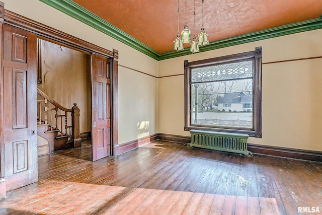 unfurnished room featuring hardwood / wood-style floors, crown molding, and radiator