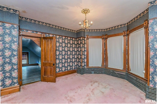 spare room featuring carpet flooring, vaulted ceiling, and a notable chandelier