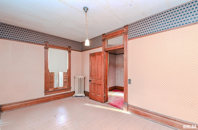 unfurnished bedroom featuring hardwood / wood-style floors and radiator heating unit