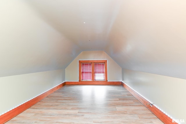 additional living space featuring light hardwood / wood-style floors and vaulted ceiling