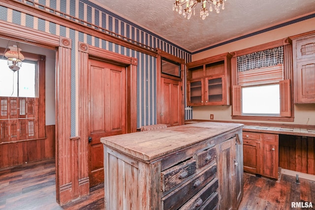 kitchen with dark hardwood / wood-style floors, a textured ceiling, crown molding, and a center island