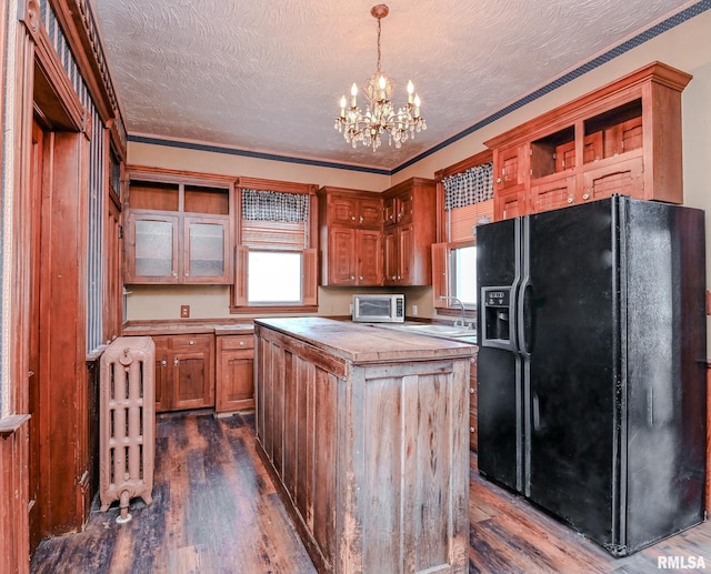 kitchen featuring a wealth of natural light, black refrigerator with ice dispenser, dark hardwood / wood-style floors, and decorative light fixtures