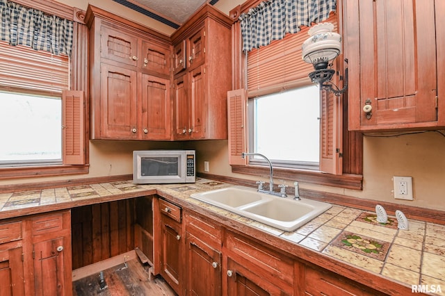 kitchen with tile counters, plenty of natural light, sink, and dark hardwood / wood-style floors