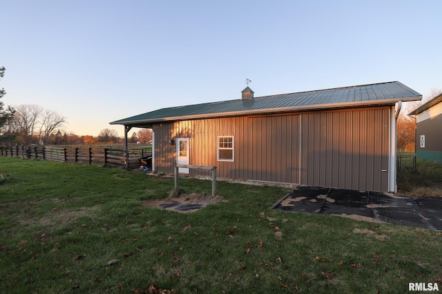 property exterior at dusk with a lawn and an outdoor structure