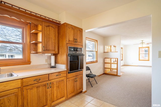 kitchen with ceiling fan, sink, black oven, and light carpet