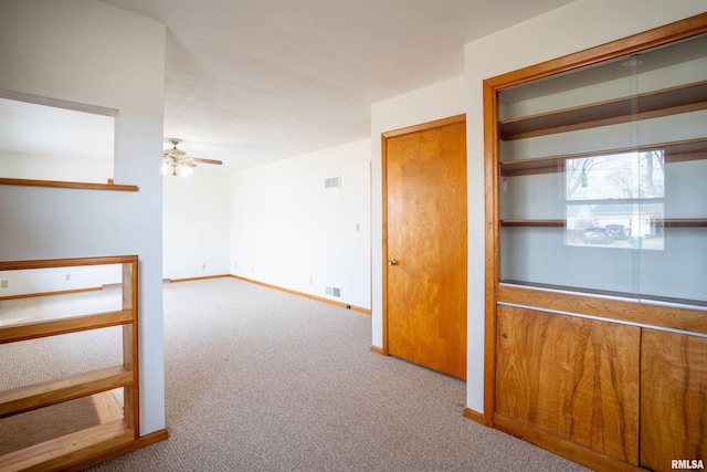 empty room featuring ceiling fan and light carpet