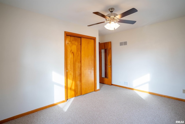 unfurnished bedroom featuring ceiling fan, light colored carpet, and a closet